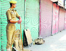  A jawan stands guard at a deserted street during a shutdown in Srinagar on Monday.