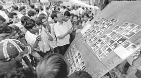 People look at the pictures of the passengers who died in the mishap.