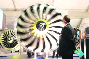 A visitor looks at a jet engine during the Farnborough International Airshow in Hampshire, southern England, on Tuesday. Brazilian aircraft maker Embraer on Tuesday announced a deal to sell up to 140 of its small jets worth $5 billion, as the Farnborough airshow order race ramped up. 