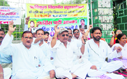 Congress workers hold a dharna against the taking over of the Rishikul Vidyapeeth for the Uttarakhand Ayurvedic University at the Gandhi Park in Dehradun