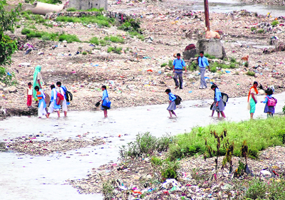 Schoolchildren cross the Rispana river in Dehradun
