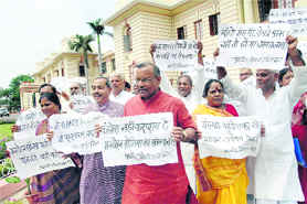 NDA legislators hold placards during a protest against price hike outside the Bihar Assembly in Patna on Tuesday.
