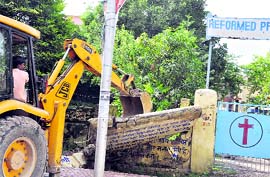A JCB machine demolishes the wall of a church in an anti-encroachment drive in Haridwar on Wednesday