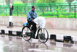 A man rides a bicycle in rain which lashed Srinagar