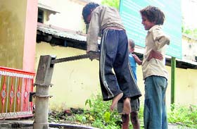 Its daily struggle for water. A street urchin pushes the handle of a handpump in the Kutchery campus of Dehradun.