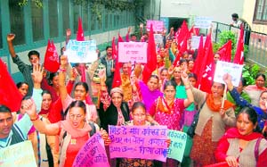 Mid-day meal workers and helpers raise slogans in support of their demands at the Directorate of Education in Shimla on Friday.