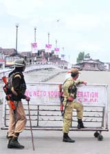 Security personnel stand guard at a barricaded road in Amarakadal in Srinagar during restrictions on Friday. 