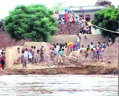 Residents of the flood-hit Gajni Wala village shift their belongings to safer places. 