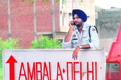 A cop on duty at Zirakpur talks on his mobile phone as the traffic eases after morning rush hours on Sunday. 