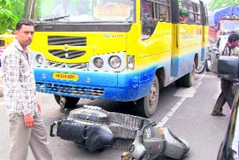 A man looks on after his scooter was hit by a bus.