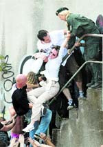 German police officers lift up a woman from the crowd of revellers outside a tunnel at the Love Parade in Duisburg on Saturday