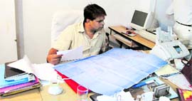 Ja Sansthan Executive Engineer DK Singh looks at the site plan of the Town Hall in Mussoorie on Monday.
