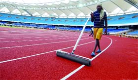 A worker clears water from the tracks at the newly-inaugurated Jawaharlal Nehru Stadium in New Delhi on Tuesday.