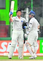 Suresh Raina (L) raises his bat towards the pavilion after completing his century as Sachin Tendulkar looks on on Thursday.