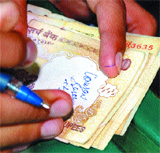 A parent mentions name of his son, class and roll number on a Rs 500 note to be deposited with the school as fee.