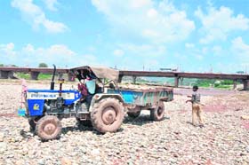 Labourers load sand and stone from the Tawi riverbed in Jammu