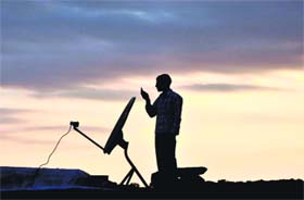 A man atop a house in the Harthama area of Kalakote tehsil in Rajouri district tries to operate his cellphone