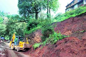 Workers clearing the road which was blocked after a landslide near RKMV College in Shimla on Monday.