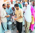 Attendants of patients at a hospital wait for their turn for food provided by volunteers in Srinagar on Monday.