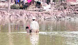 A Pakistani man holds on to his son as he wades through floodwaters in Kamp Koroona village near Nowshera on Monday.