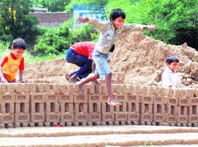 Children of labourers play at a brick kiln in Mullanpur village