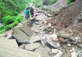 Residents of Khatta Pani find their way on a road destroyed by incessant overnight rain in Mussoorie