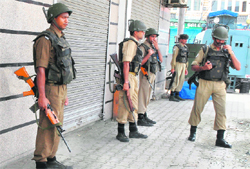 CRPF jawans keep a vigil in front of a closed shop at the Lal Chowk in curfew-bound Srinagar
