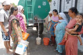 People line up to collect water supplied by a water tanker at the Chandan Nagar area in Jalandhar