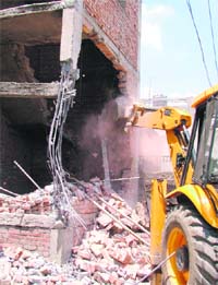 An illegal building being razed by municipal corporation in Ludhiana on Tuesday