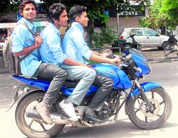Schoolboys ride triple on two-wheelers without helmet on the road separating Sectors 20 and 30 in Chandigarh