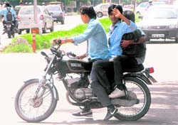 Schoolboys ride triple on two-wheelers without helmet on the road separating Sectors 20 and 30 in Chandigarh