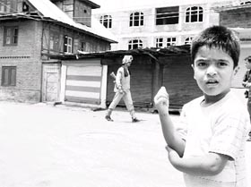 A school boy wanting to be in school looks around in a deserted market in Srinagar on Wednesday.