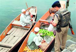 A CRPF jawan buys vegetables from a vendor on the Dal Lake in curfew-bound Srinagar on Thursday