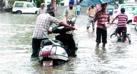 People walk through a flooded street in Amritsar.