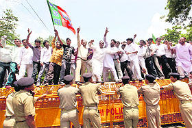 BJP activists stand on police barricades to protest against alleged corruption in Games-related works in New Delhi on Friday.