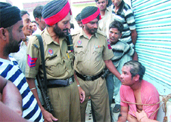 Policemen look at the boy, who was beaten up and tonsured by residents at Mithu Basti in Jalandhar 