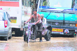 A rickshaw puller on a waterlogged street in Dehradun on Saturday.