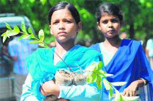 A girl carries away saplings from the event in Karnal on Saturday.