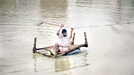 PAK DELUGE: A Pakistani uses a cable wire to cross a deep flooded area of Kot Addu on Sunday. 