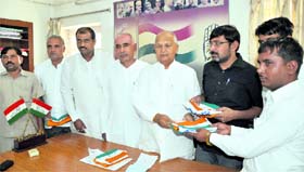 HPCC president Phool Chand Mullana presents the Congress flag to husbands of two women zila parishad members at a function at the Congress office in Chandigarh on Tuesday.