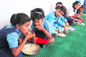 Children eat food under the mid-day meal scheme in Government Model School, Satwari