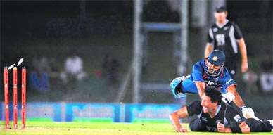 Daryl Tuffey (bottom) successfully runs out MS Dhoni in Dambulla on Tuesday.