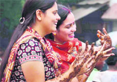 Two women admire the henna patterns on their palms on the occasion of Teej in Haridwar on Thursday.