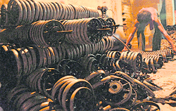A worker at a sewing machine unit collects wheel handles.
