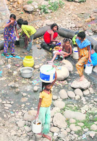 Children collect water from a leaking pipe on the bypass road at Narwal in Jammu. 