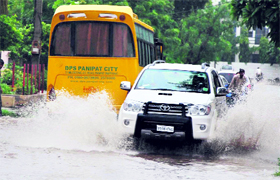 Vehicles move through a flooded road after heavy rain in Karnal on Saturday.