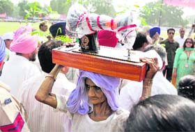 A poor woman carries a sewing machine given to her on the occasion of Independence Day function in Ludhiana