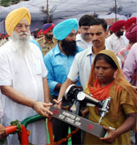 Rural Development and Panchayat Minister Ranjit Singh Brahmpura, distributes a sewing machine to a widow during the Independence Day function in Amritsar.