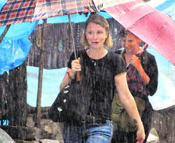 Some foreigners hold umbrellas to protect themselves from rain at Bhagsu Nag, near Dharamsala, on Tuesday.
