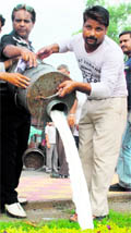 Officials of the Jammu Municipal Corporation destroy milk during an anti-adulteration drive at the Tawi Bridge in Jammu on Tuesday